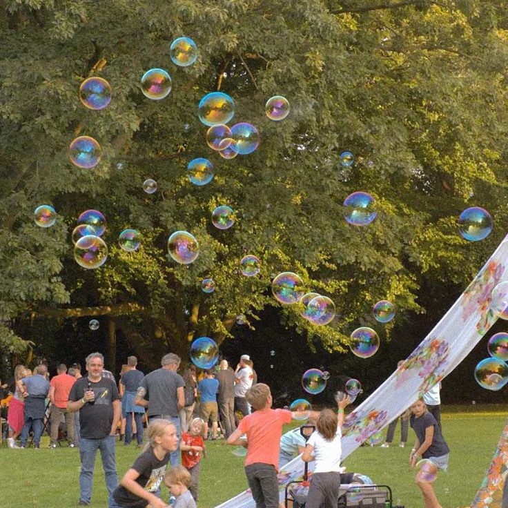 bellenblaas workshop Kinderen spelen en lachen in een park terwijl zeepbellen door de lucht zweven.